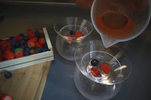 pouring champagne jelly into glasses with berries