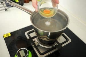 adding egg to vinegar water to poach an egg