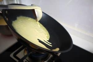 pouring batter to make crepes