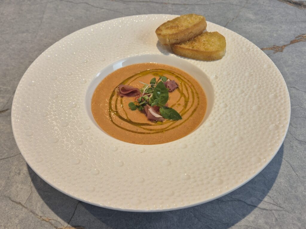 Bright red gazpacho soup served in a bowl with fresh cucumber, tomato, and herbs – refreshing summer Spanish dish.