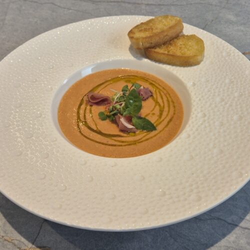 Bright red gazpacho soup served in a bowl with fresh cucumber, tomato, and herbs – refreshing summer Spanish dish.