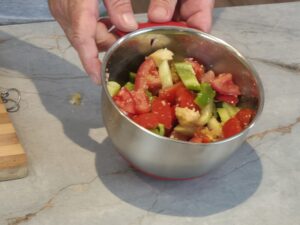 Fresh tomatoes, cucumbers, bell peppers, garlic, and olive oil on a cutting board – ingredients for homemade gazpacho